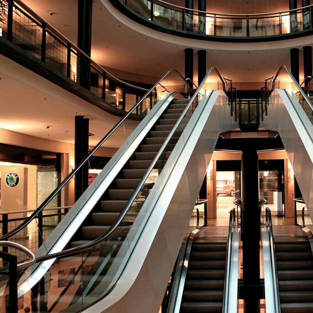 Symmetrical view of escalators in a modern shopping mall interior, showcasing architecture and design.