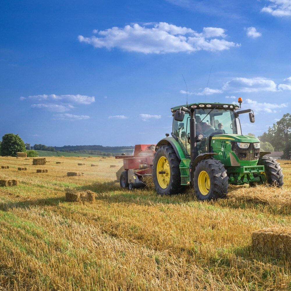 green tractor on brown grass field under blue sky during daytime
