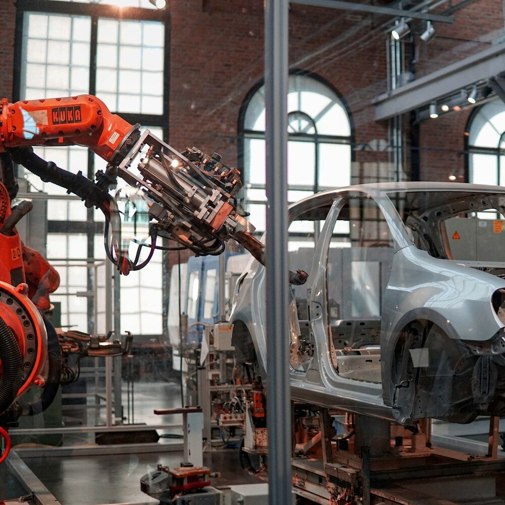 gray vehicle being fixed inside factory using robot machines